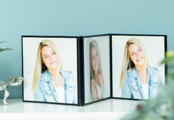Trifold photography folio display showcasing senior portrait prints standing upright on a styled surface