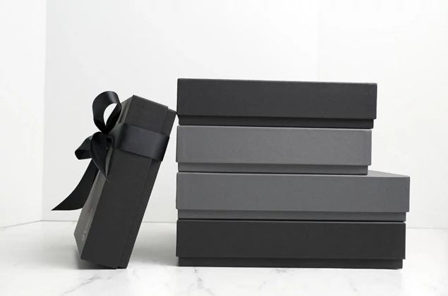 Two matte black album boxes in different sizes with black ribbon on marble surface     Tyndell album box size comparison