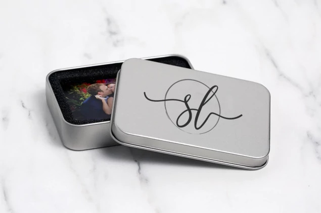 Metal tin box open with foam insert holding a flash drive showing USB delivery configuration