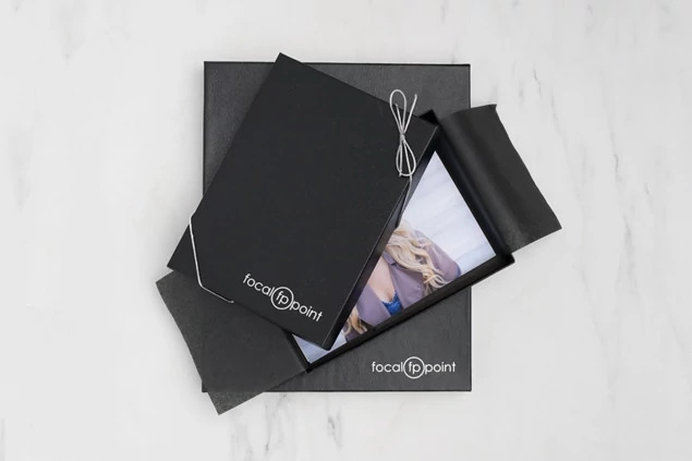  Open black leather portrait box with portrait print and studio logo, displayed on marble surface     Tyndell