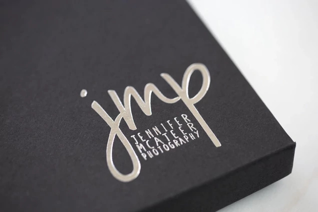 Close-up of matte black deluxe portrait box lid with custom foil imprinted studio logo     Tyndell portrait packaging