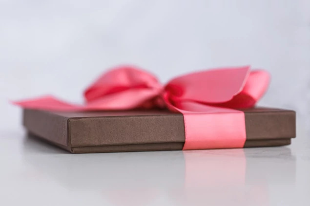 Matte chocolate deluxe portrait box closed with pink satin ribbon showing slim raised lid profile     Tyndell portrait packaging
