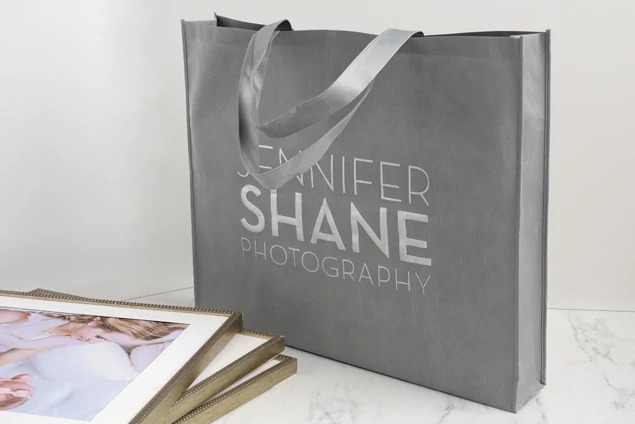 Slate gray frame bag close-up showing nonwoven fabric construction and reinforced shoulder handles