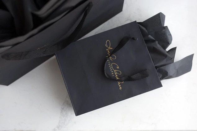 Close-up of black Euro Tote bag showing cotton twill ribbon handles and foil imprinted studio logo