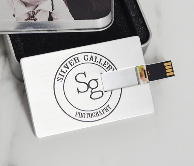 Silver metallic credit card flash drive with full-color photo printed on front showing hinged USB design