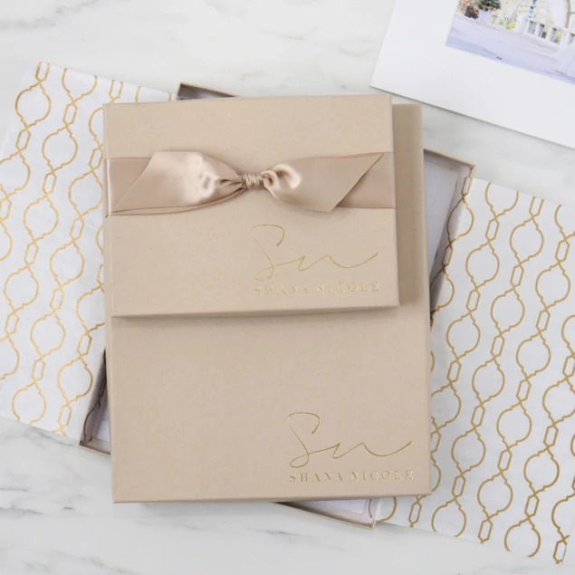 Kraft deluxe portrait box with custom foil studio logo and champagne ribbon on gold patterned tissue paper     Tyndell
