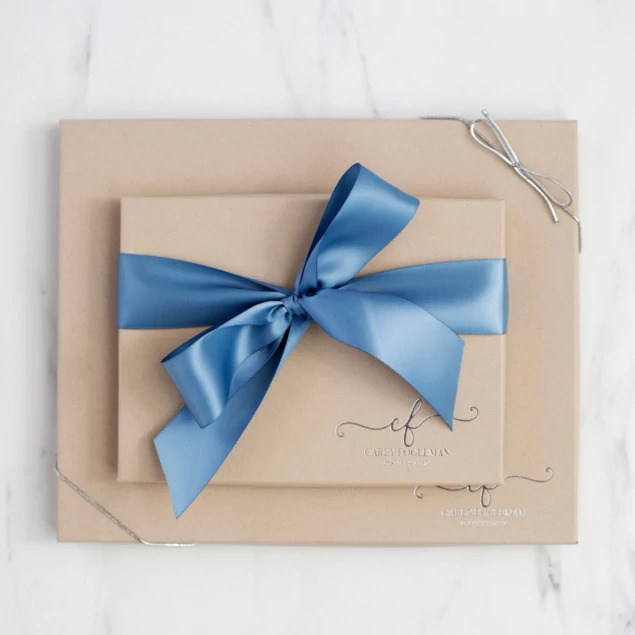 Kraft deluxe portrait box with custom foil studio logo and blue satin ribbon on marble surface     Tyndell