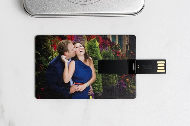 Black metallic credit card flash drive with full-color photo printed on front showing hinged USB design