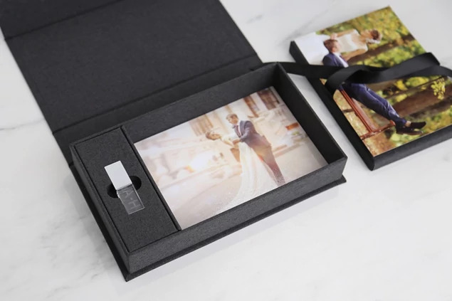 Carbon fabric flash and print box open with prints fanned out showing capacity and satin ribbon