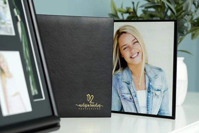 Berkley Folio open showing gold foil studio logo imprinting on black simulated leather cover with senior portrait inside