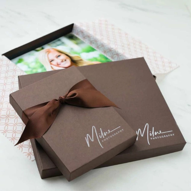 Open matte chocolate portrait box with senior portrait print and brown ribbon on patterned tissue paper     Tyndell