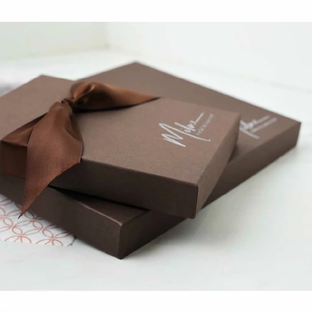 Close-up of matte chocolate portrait box with custom foil imprinted studio logo and brown ribbon     Tyndell portrait packaging