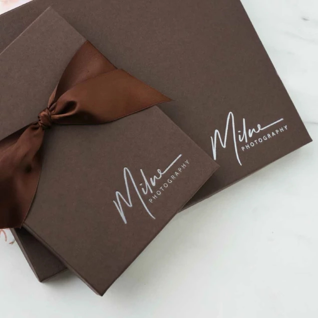 Matte chocolate portrait box closed with brown ribbon and custom foil studio logo     Tyndell