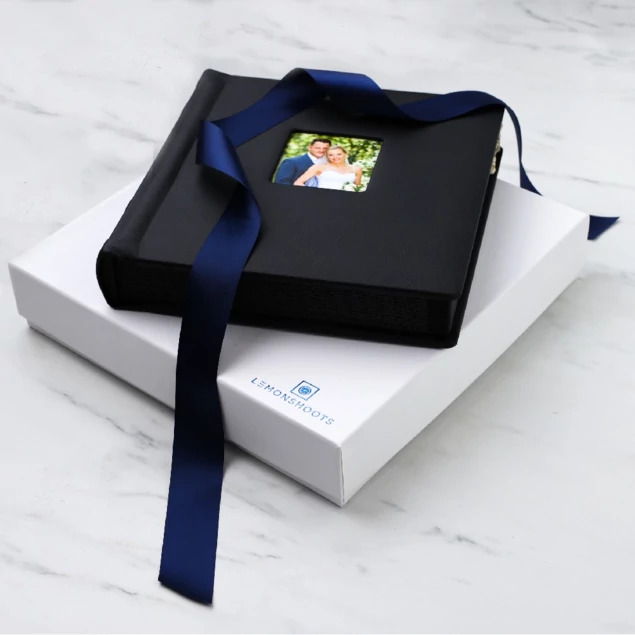 Open white soft touch album box with square album inside and navy ribbon     Tyndell album packaging