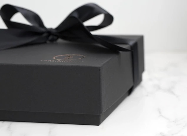 Matte black album box with custom foil studio logo and black ribbon on marble surface     Tyndell album box