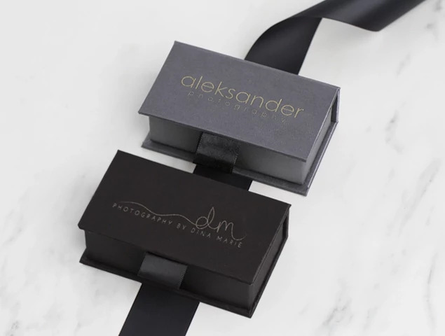 Slate and black fabric USB boxes shown together displaying taffeta fabric exterior and ribbon tab detail