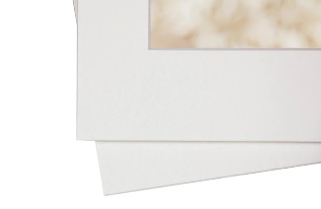 Stack of archival portfolio mats showing soft white linen texture finish     Tyndell portrait mats