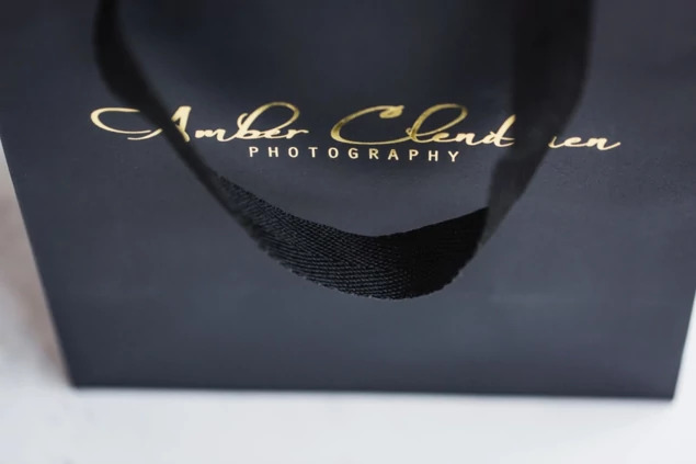 Black Euro Tote bag close-up showing foil imprinted studio branding and cotton twill handle detail