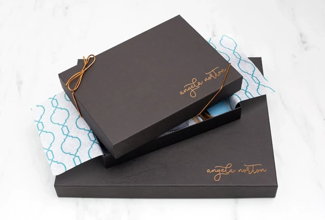 Open black leather portrait box with portrait print and studio logo, displayed on marble surface     Tyndell