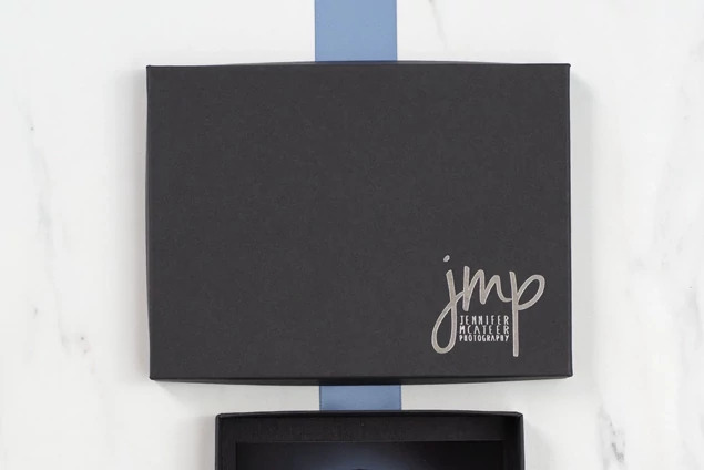 Matte black deluxe portrait box upright showing custom foil studio logo and slim profile     Tyndell