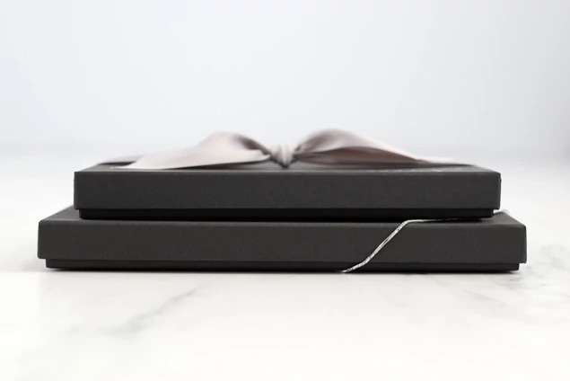 Two matte black deluxe portrait boxes stacked in different sizes on marble surface     Tyndell portrait box size comparison