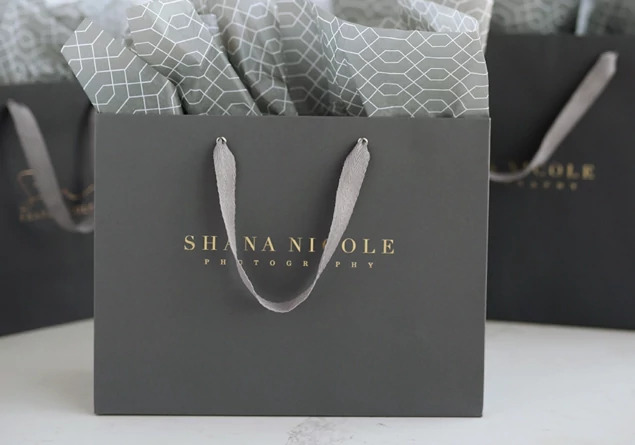 Slate gray Euro Tote bag with tissue paper and foil imprinted studio logo showing cotton twill handles